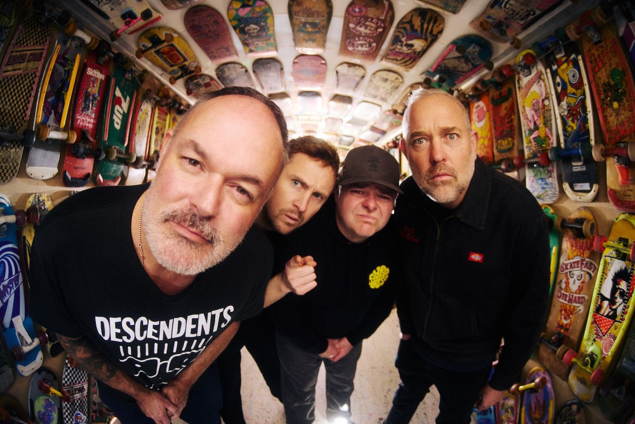 Fisheye lens shot of Australian punk rock band Bodyjar leaning toward the camera inside a room lined with vintage skateboard decks.